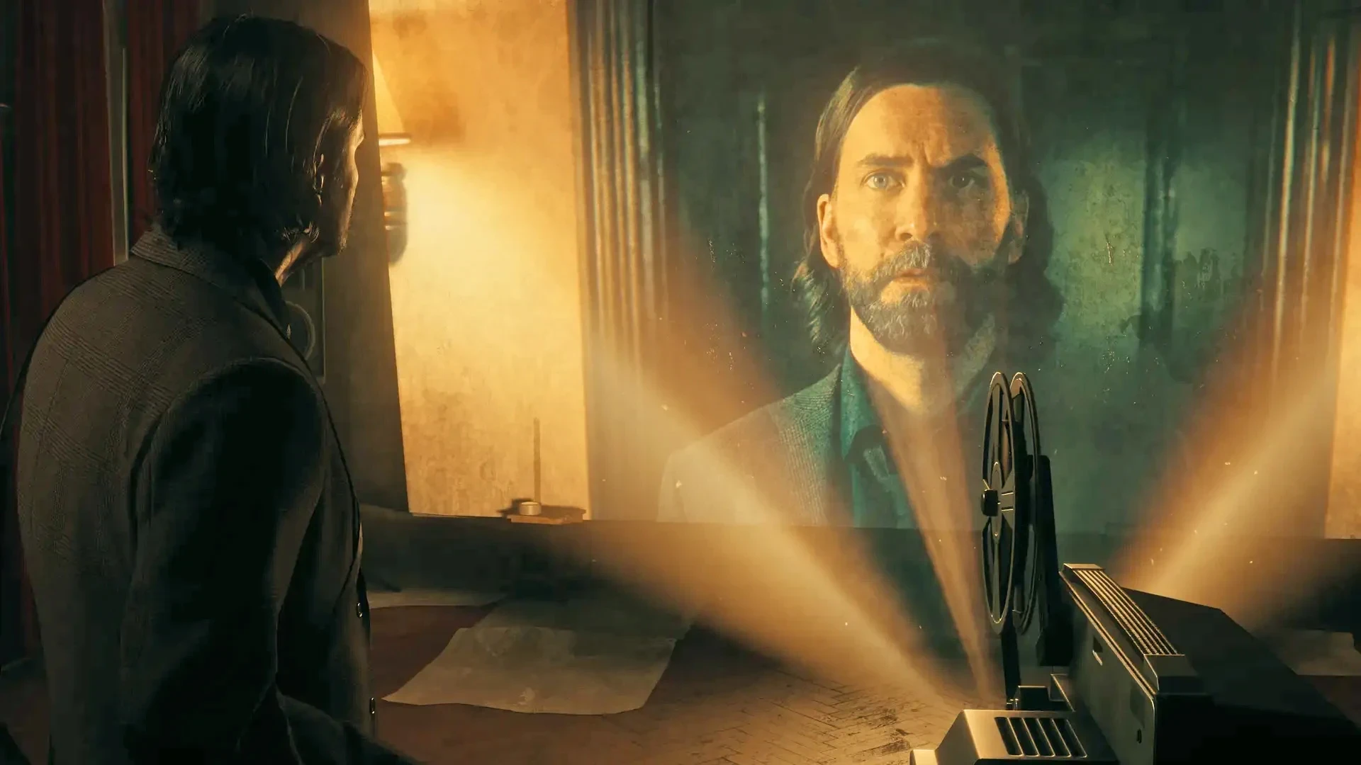 A man watches a film projector cast the glowing image of a bearded man onto the wall of a dim, warmly lit room.