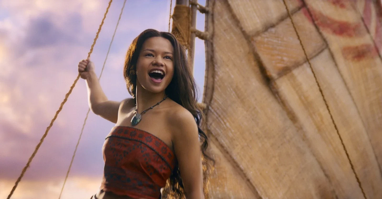 Moana, played by Catherine Laga'aia, laughs while holding a rope on her sailing canoe in Disney's live-action remake.