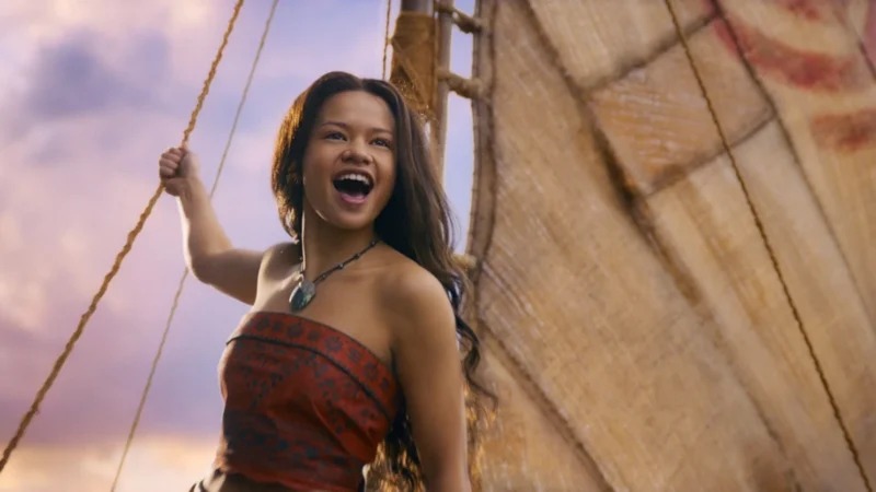 Moana, played by Catherine Laga'aia, laughs while holding a rope on her sailing canoe in Disney's live-action remake.