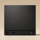 Valve's black, cube-shaped Steam Machine seen from the front, with two USB-A ports, a microSD card slot, and a power button along its base.